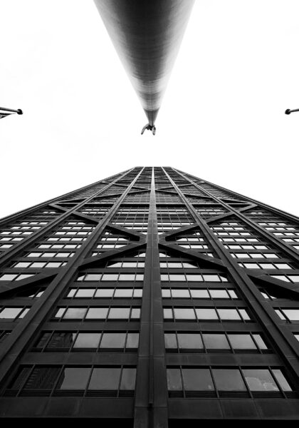 Black and white image of tall building shooting upward from the ground.